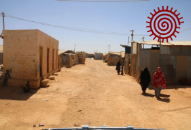 Women and children on a sandy street with concrete and corrugated iron buildings in an IDP settlement in Somalia. Abdi Omar, Somali Institute for Development Research and Analysis (SIDRA).